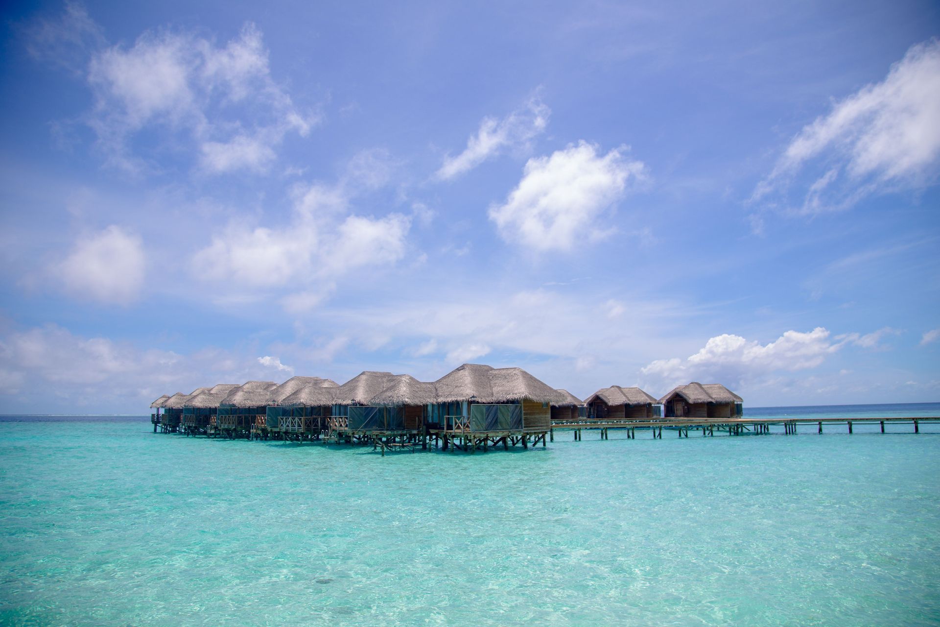 Overwater bungalows on turquoise sea under a bright blue sky