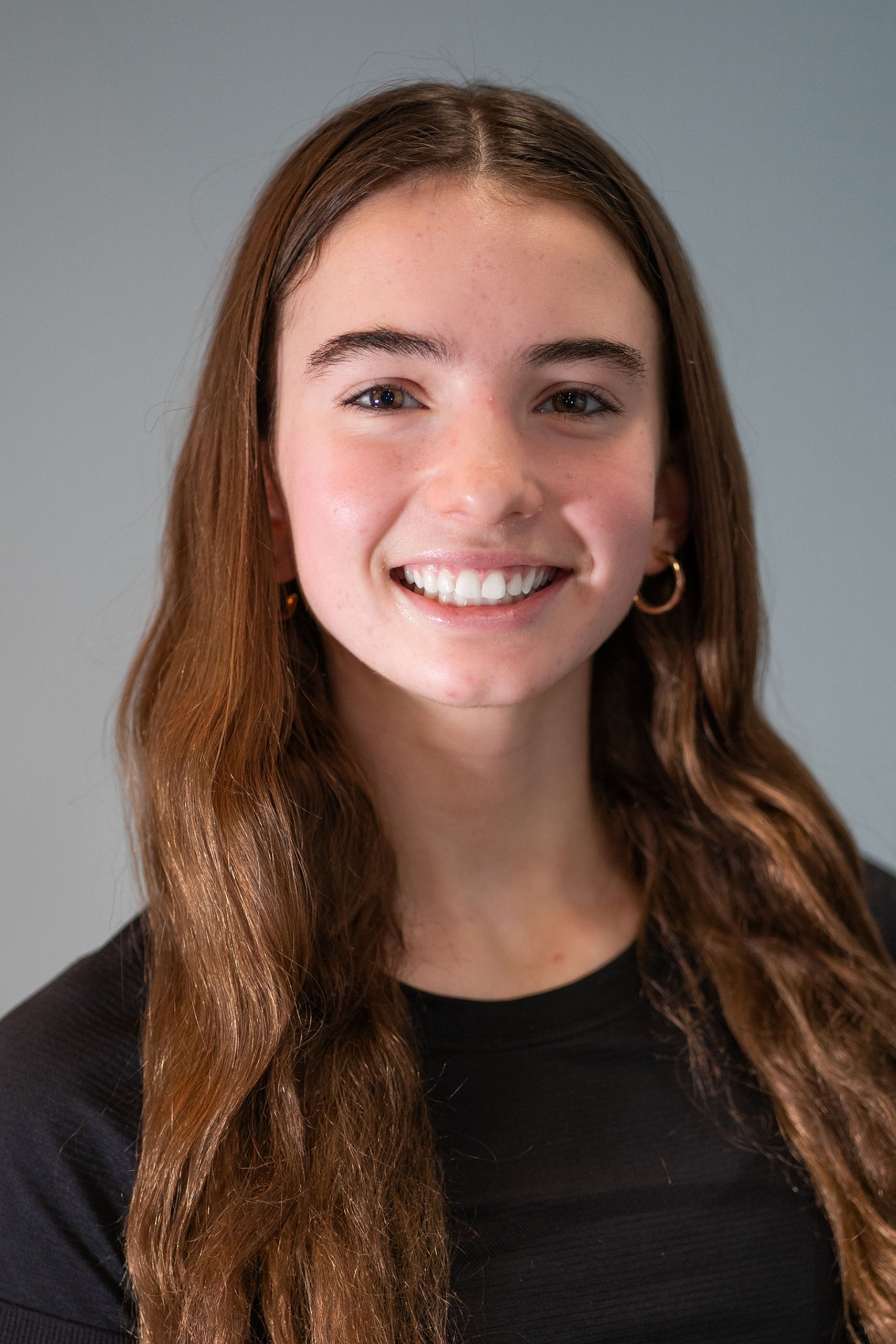 A young woman with long brown hair is smiling for the camera.