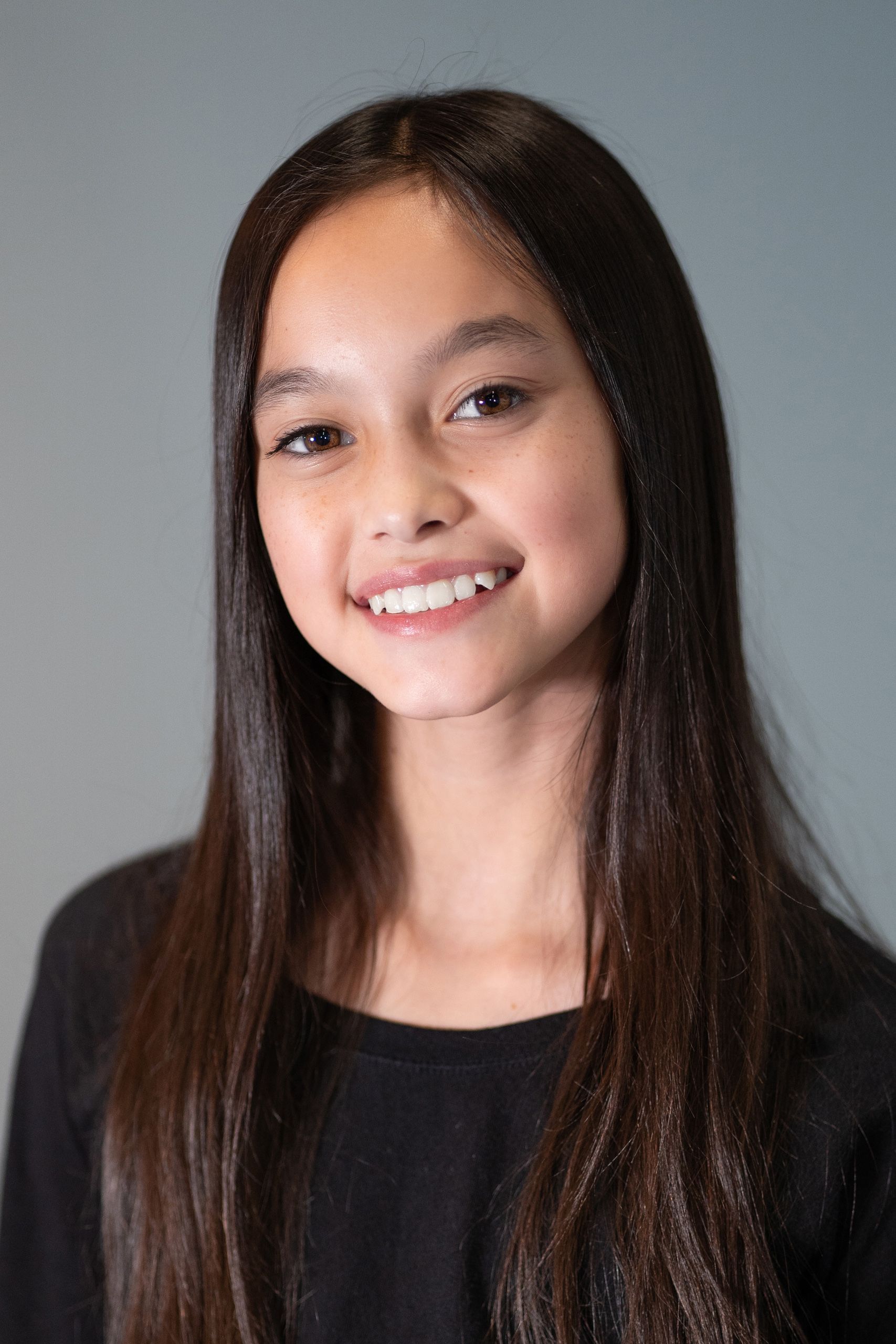 A young girl with long brown hair is smiling for the camera.