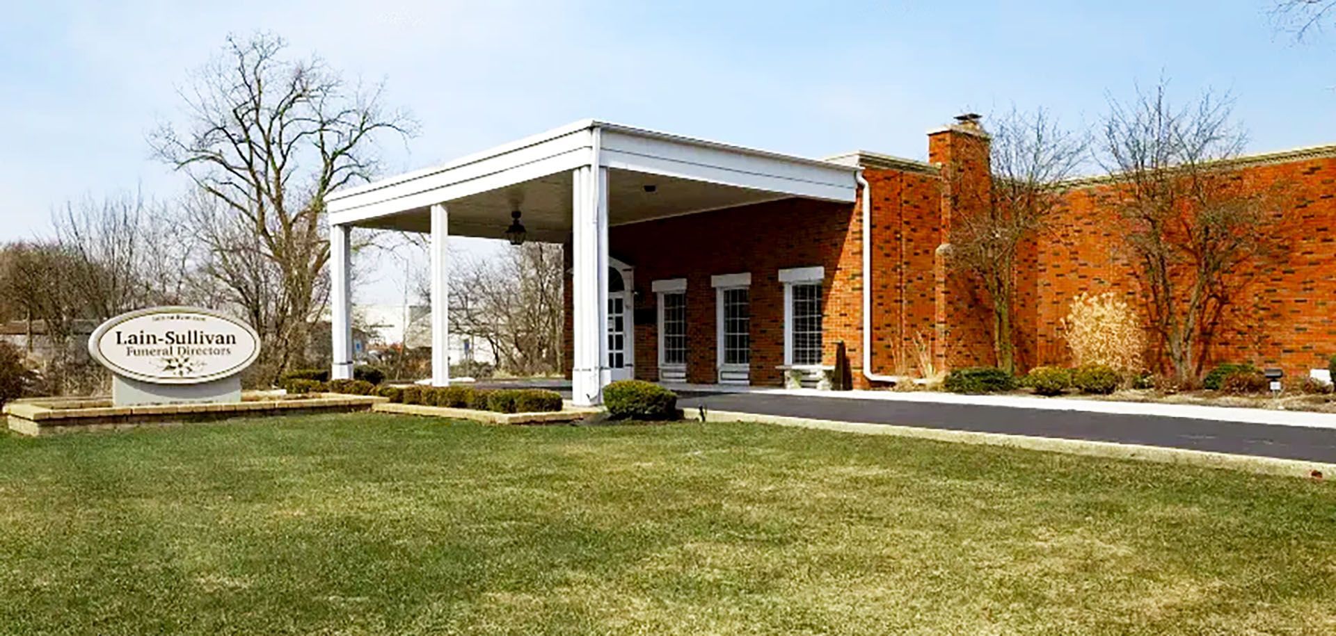 Brick building entrance with white portico and lawn in front
