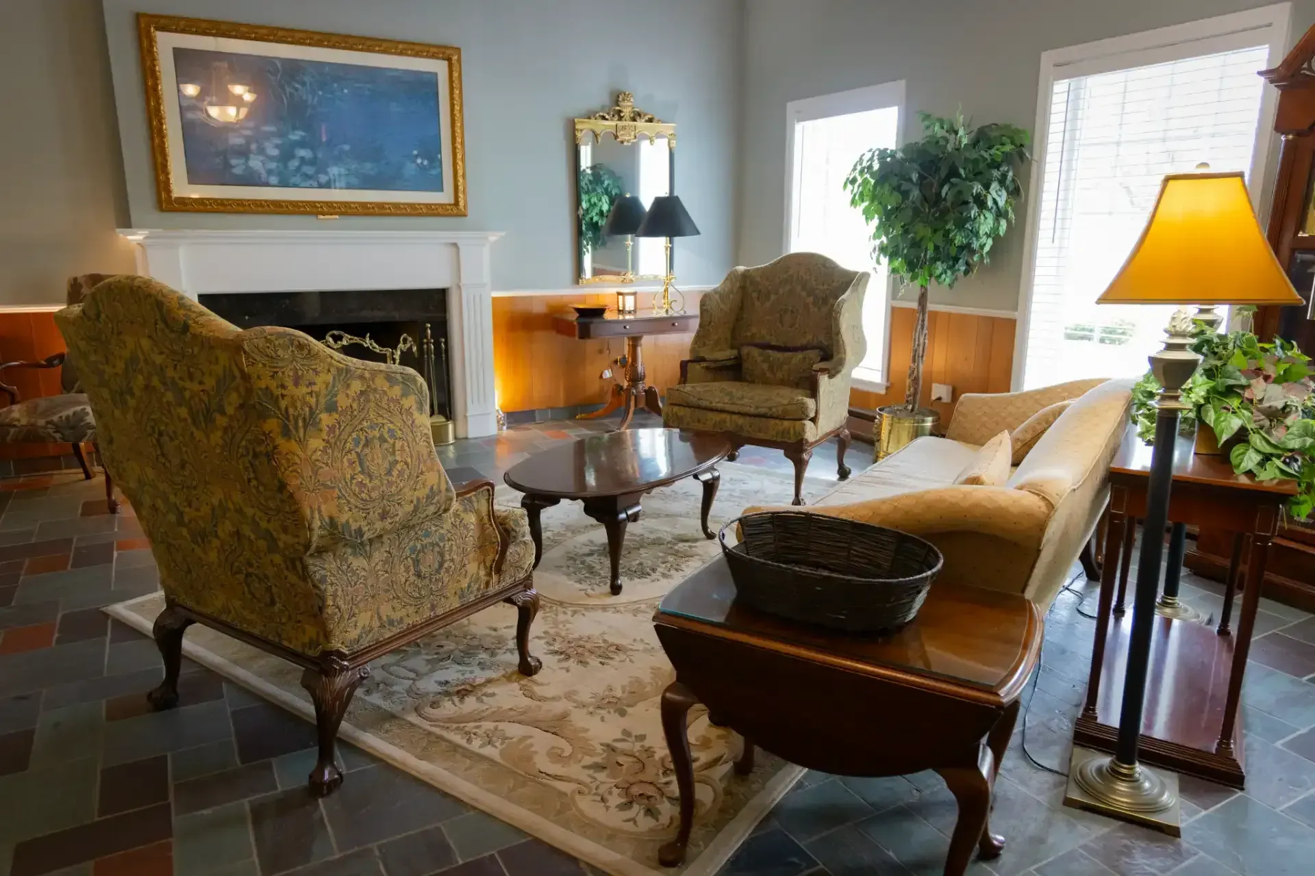 Elegant living room with patterned chairs, sofa, fireplace, lamp, and potted plant