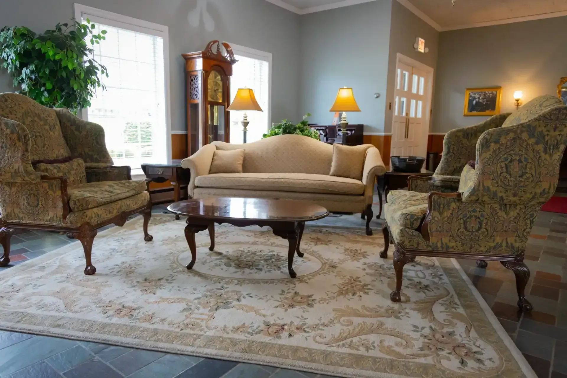 Elegant living room with beige sofa, patterned armchairs, coffee table, and soft lamps on a large rug.