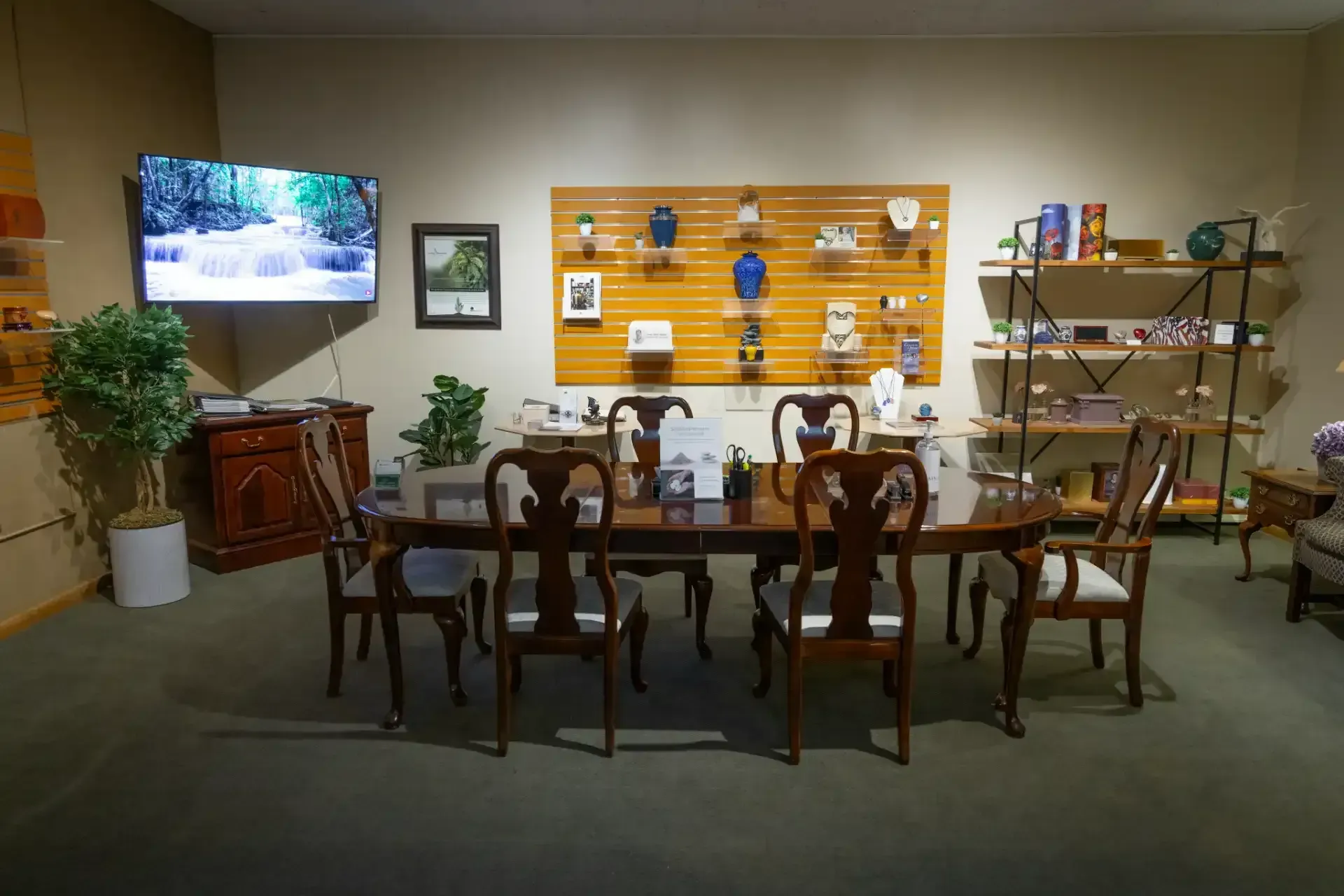 Dining room display with wooden table, chairs, wall shelf, TV, and decor in a showroom setting