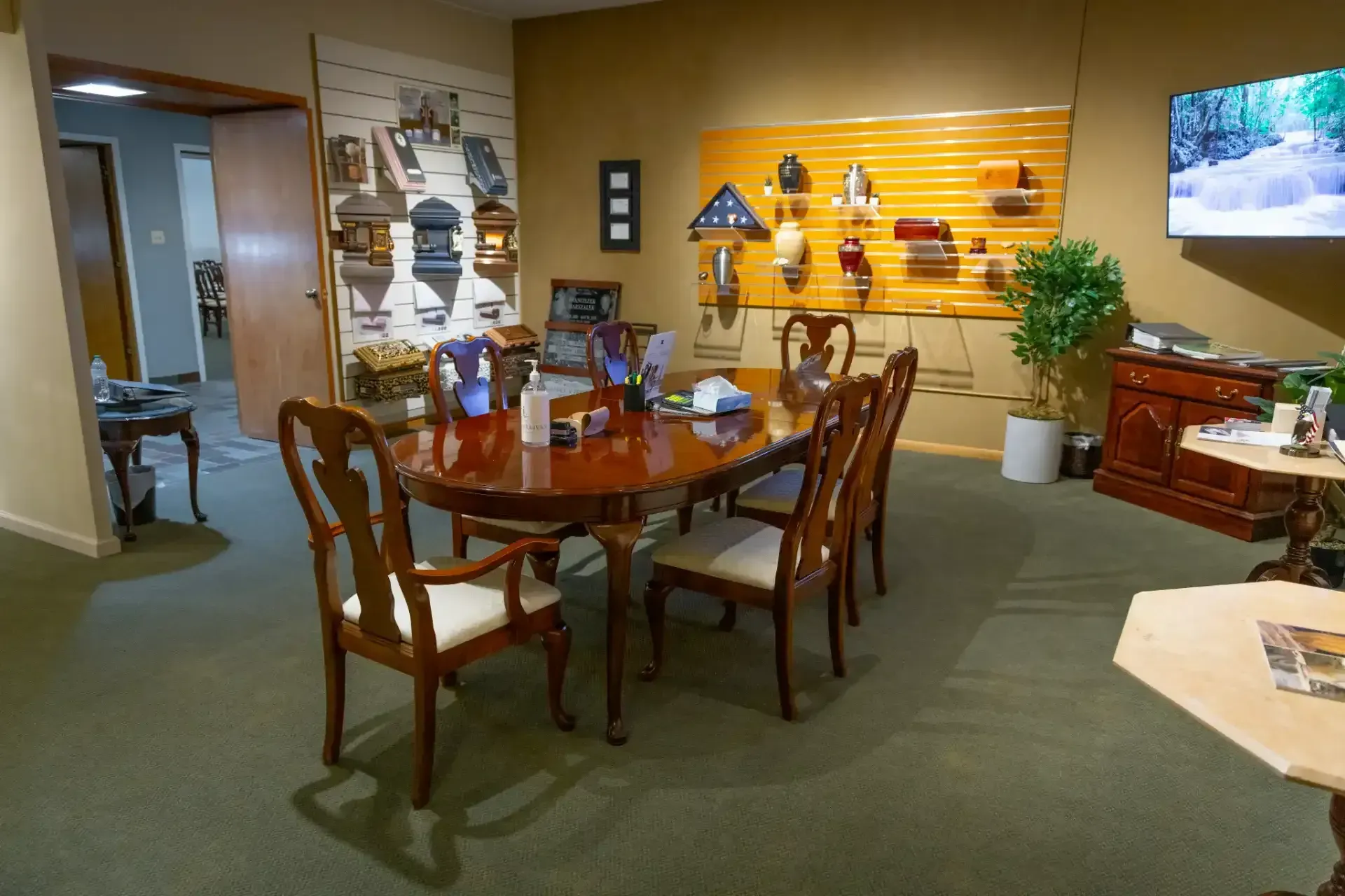 Dining room with wooden table and chairs, wall display, and TV in a cozy office lounge