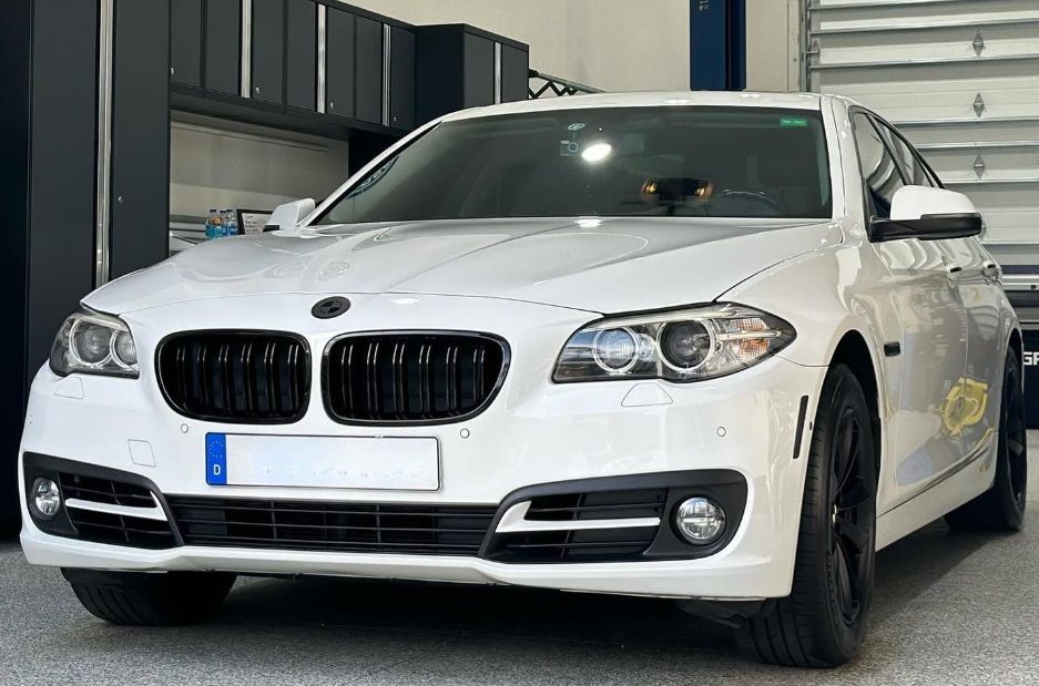 White BMW sedan parked indoors in a garage, front view