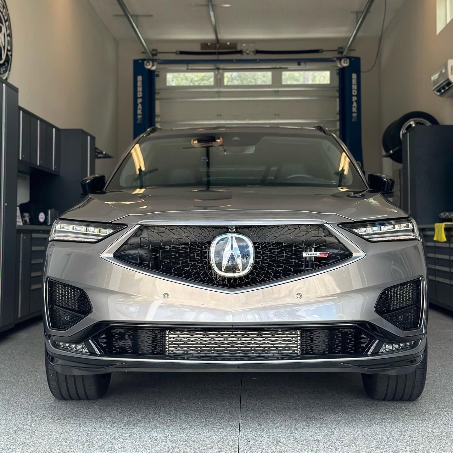 Silver Acura SUV parked in a garage with its hood open, front view