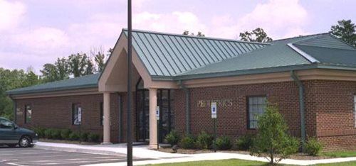 Brick building with a green metal roof, a sign, and a parking space.