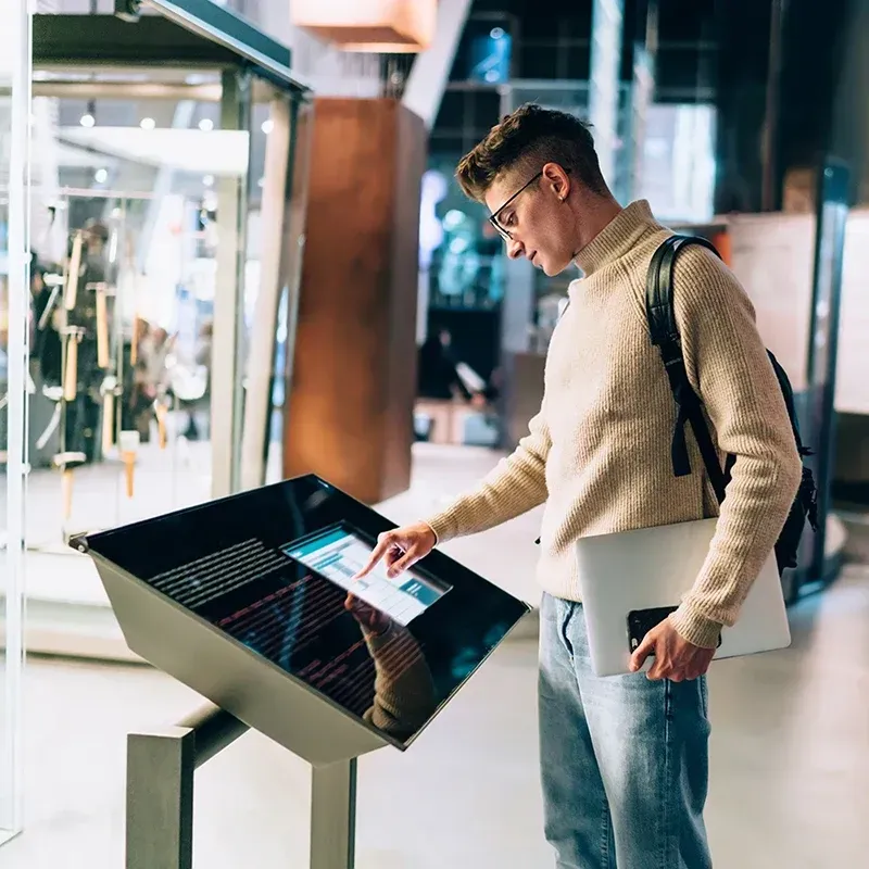 Ein Mann benutzt in einem Museum einen Touchscreen.