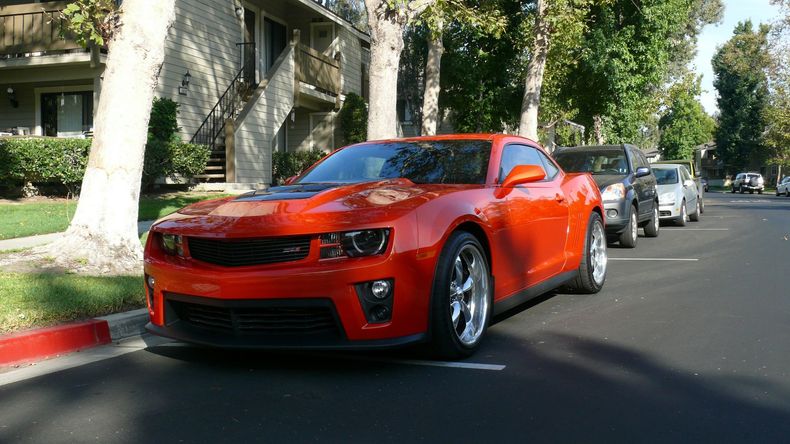 A red sports car is parked on the side of the road