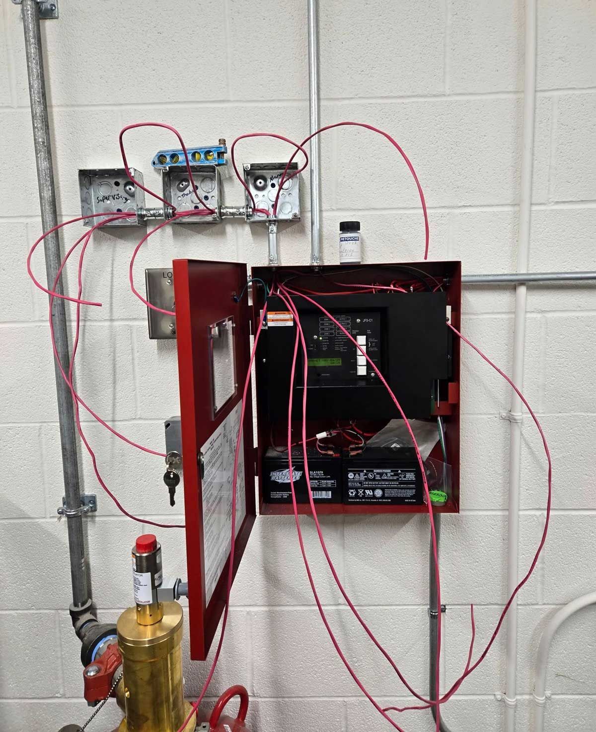 A fire hydrant is connected to a box with wires coming out of it