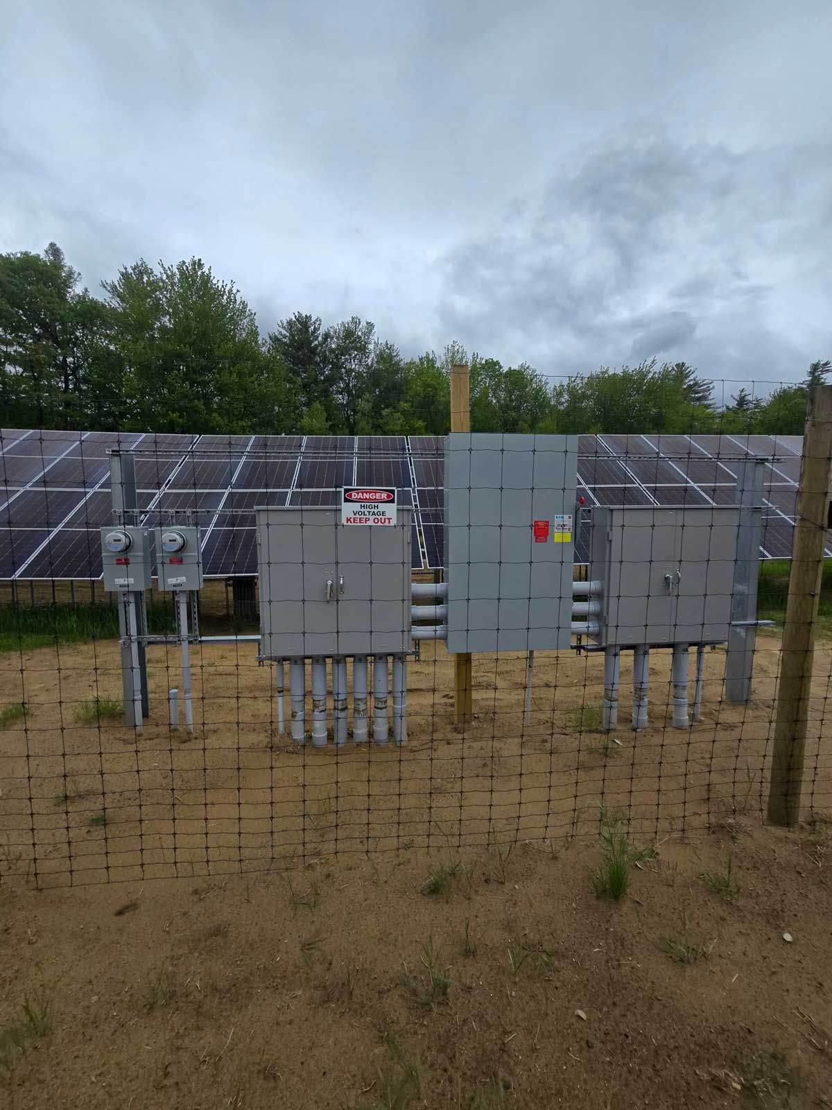 A fenced in area with a lot of solar panels and electrical boxes.