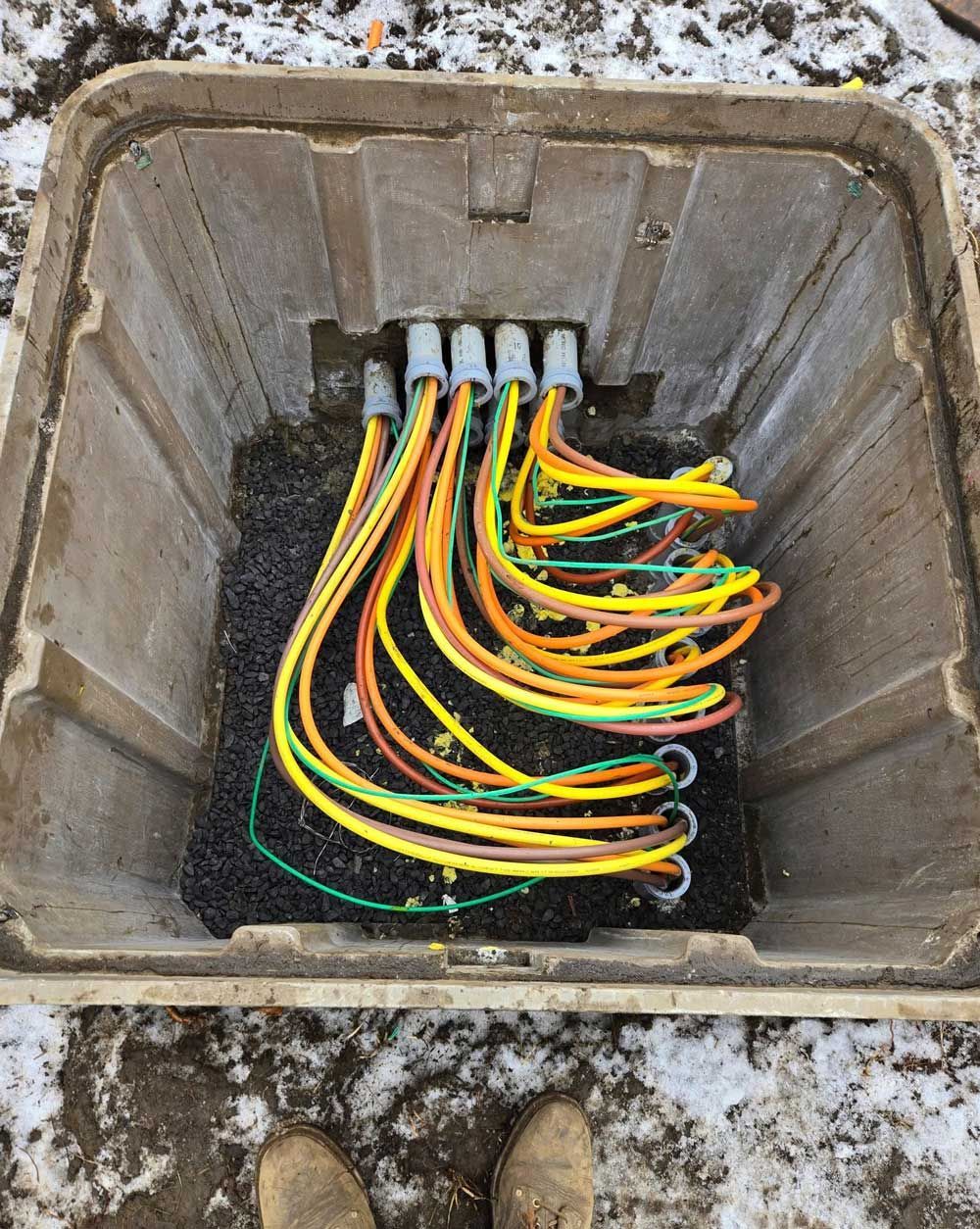 A person is standing next to a box filled with electrical wires.