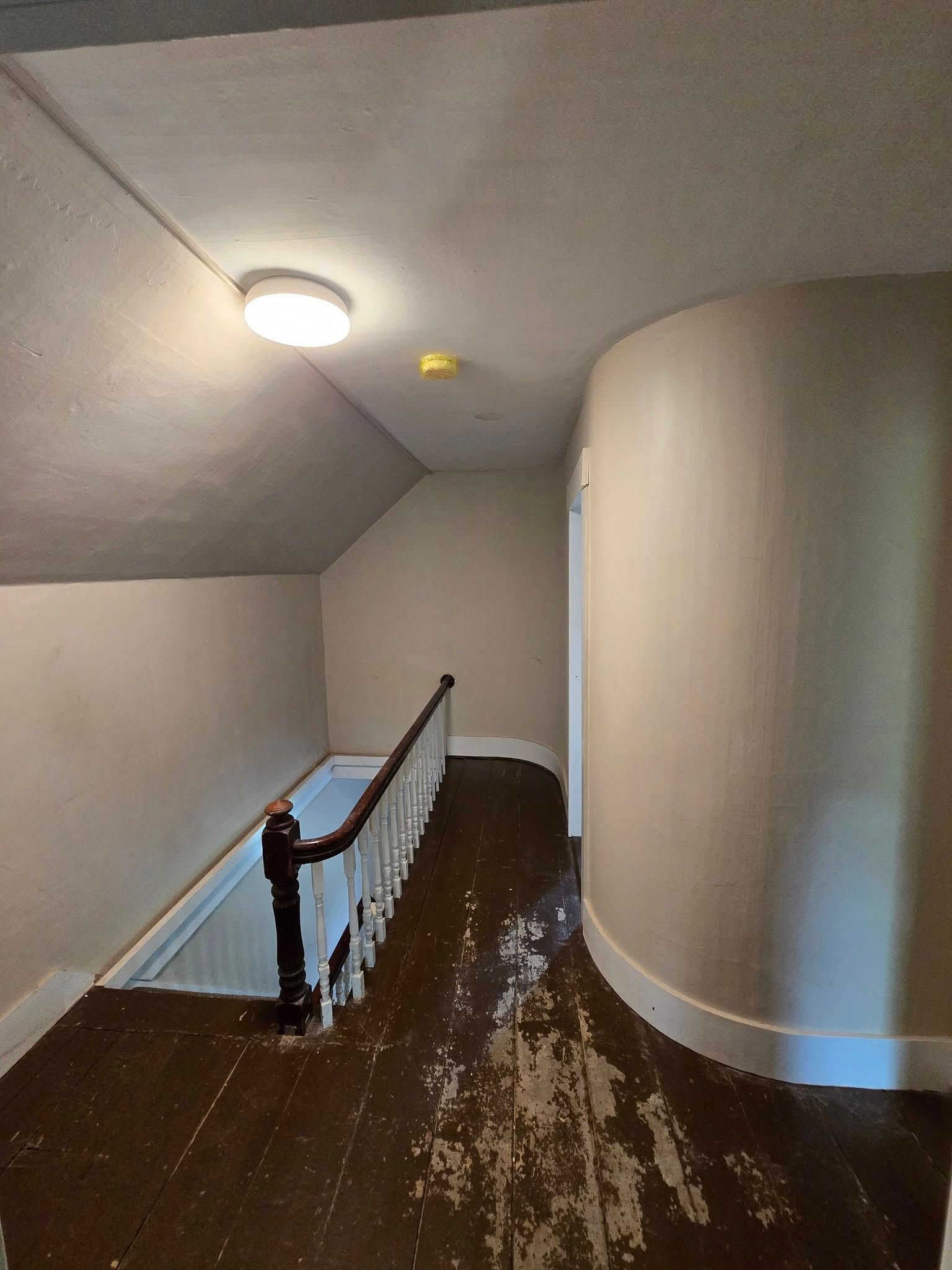 A hallway with stairs and a light on the ceiling.