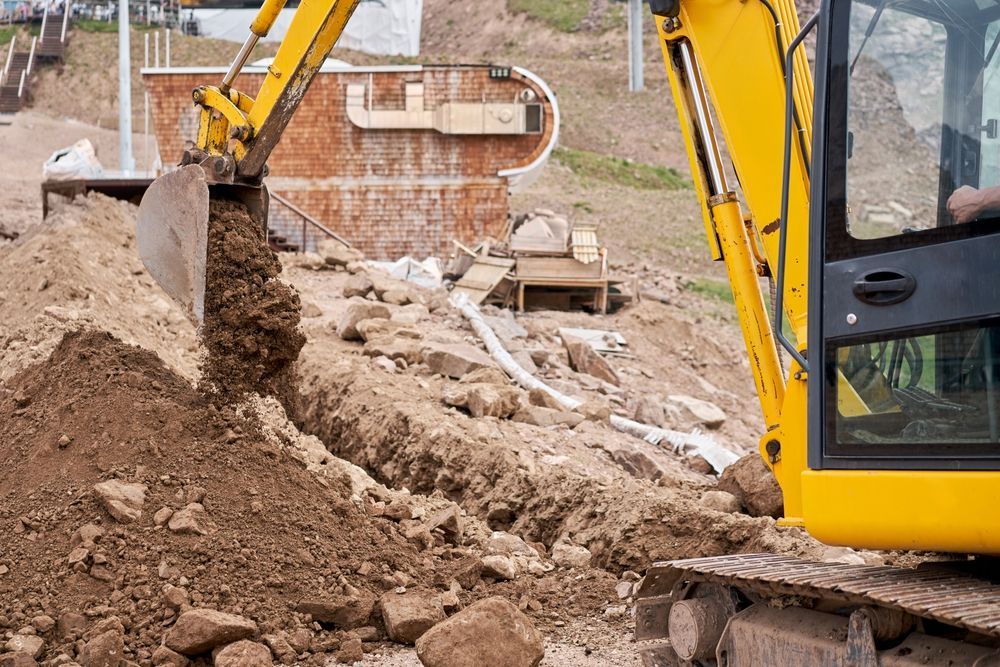 Yellow Excavator Digging a Trench in Dirt, Near a Concrete Structure — Jim Anderson Earthmoving Pty Ltd In Harrington, NSW
