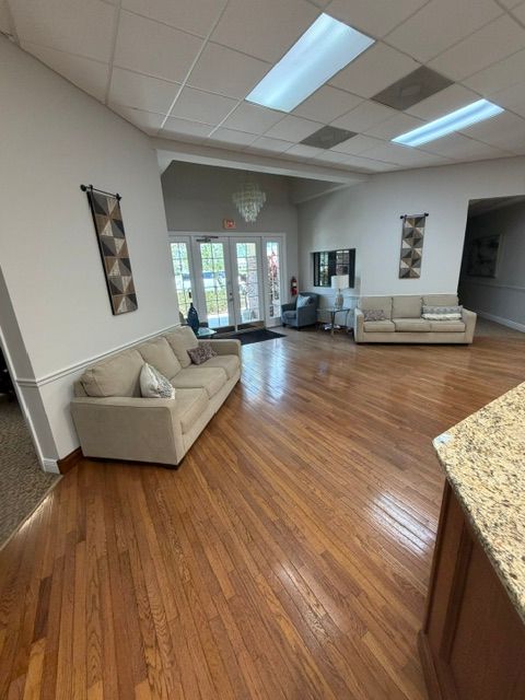 Bright lobby with beige sofas, wood floors, skylights, and glass doors leading outside