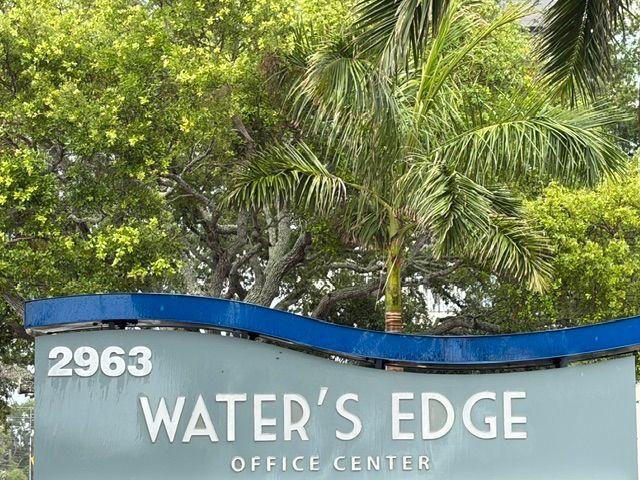 Water’s Edge office center sign beneath palm trees, with address 2963.
