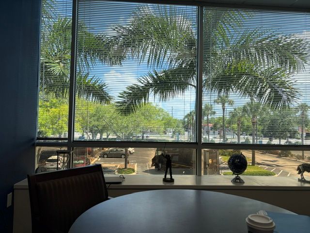 Restaurant table by a large window overlooking palm trees and a sunny outdoor patio.