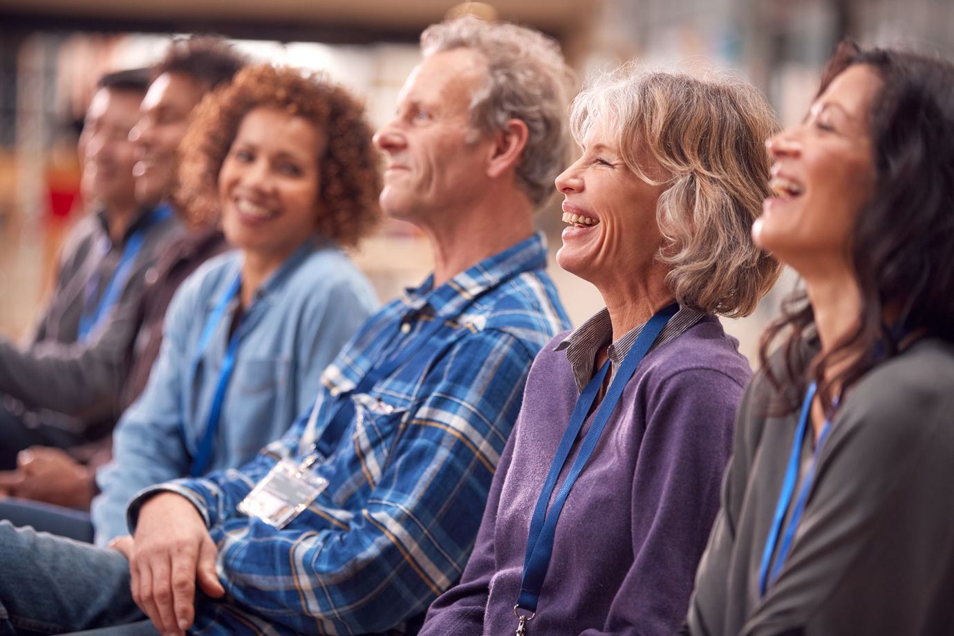 Audience seated at a conference, smiling and listening attentively in a warmly lit room