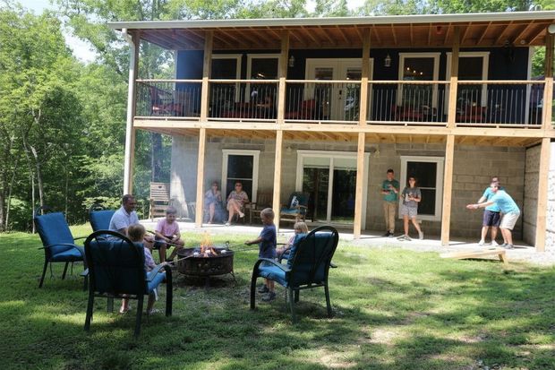 People relaxing on lawn chairs outside a two-story wooden house with a porch