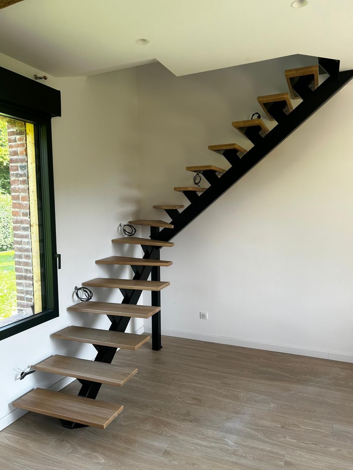 Intérieur moderne avec escalier en bois et structure en métal noir.
