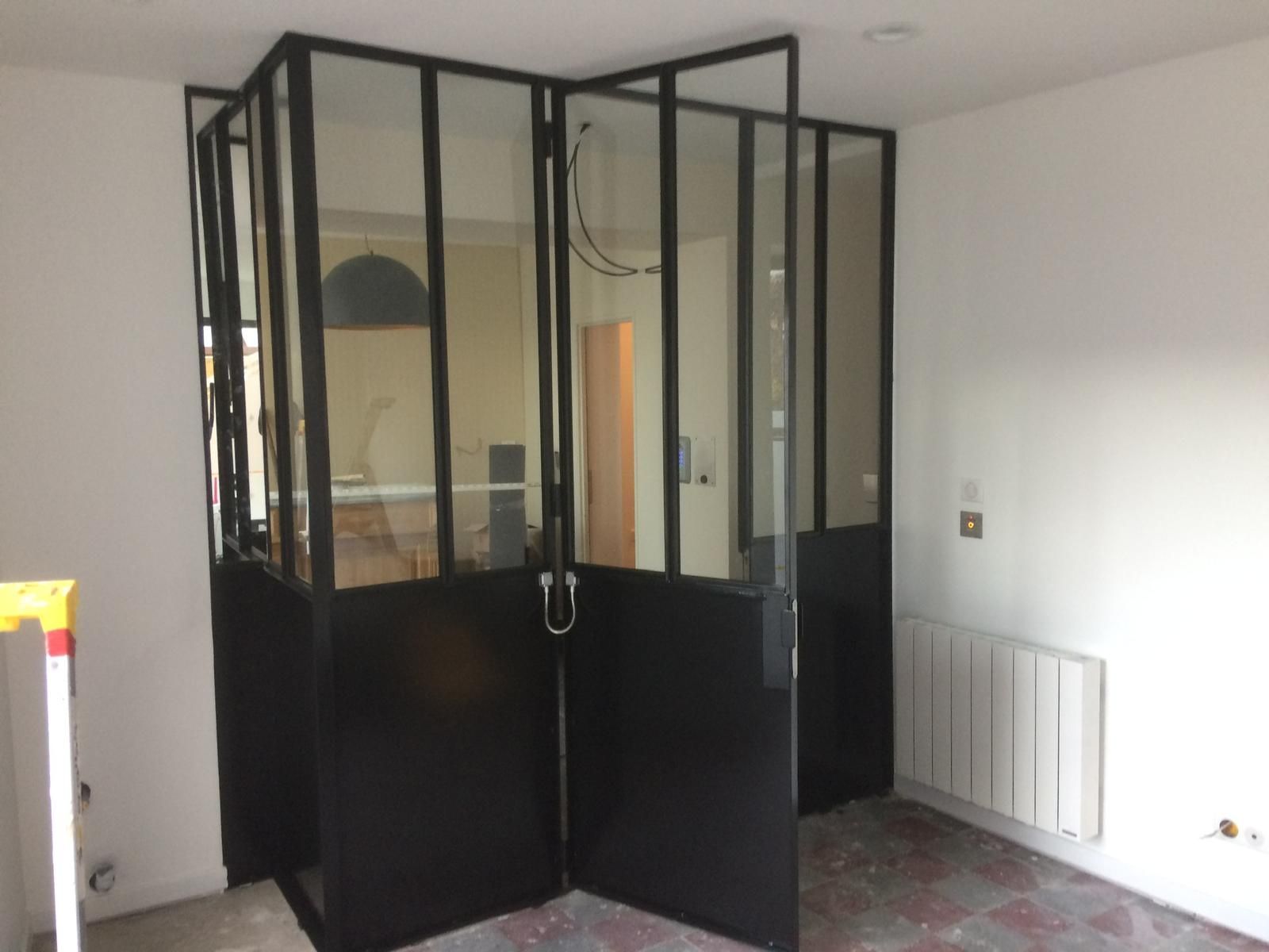 Cloisons en verre avec cadre en acier noir dans une pièce blanche ; portes ouvertes.