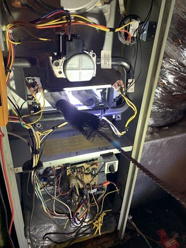 The inside of an air conditioner with a lot of wires and a brush.