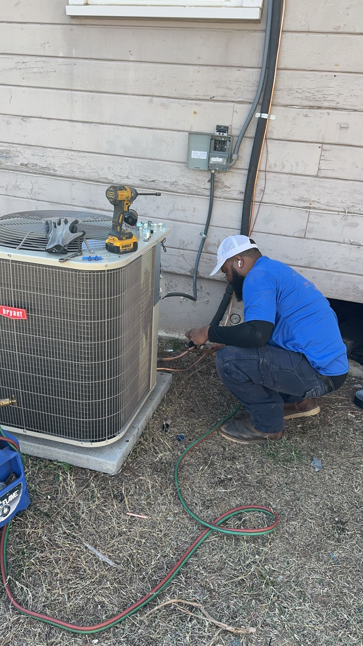 A man is working on an air conditioner outside of a house.
