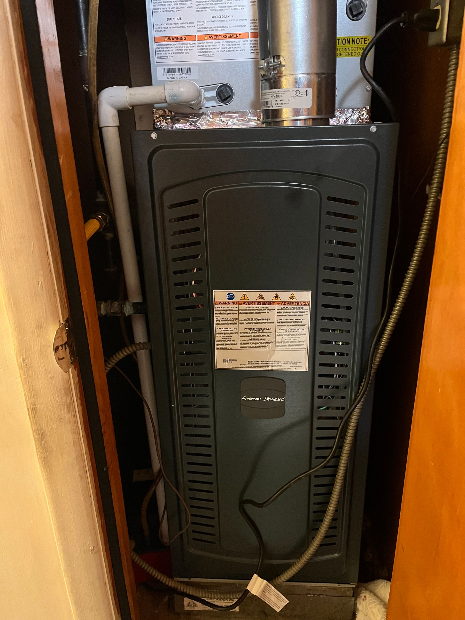 A furnace is sitting in a closet next to a door.