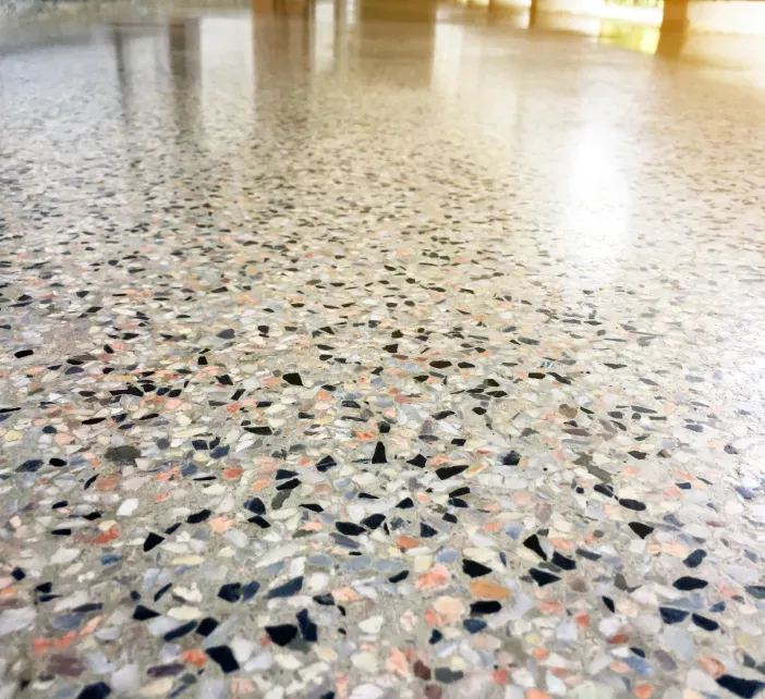 Polished terrazzo floor with multicolored stone chips and bright light reflections