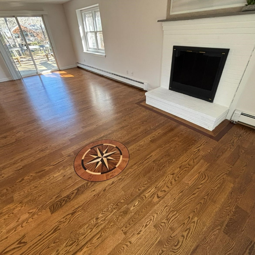 Empty living room with hardwood floors, fireplace, and a decorative floor vent near sliding glass doors