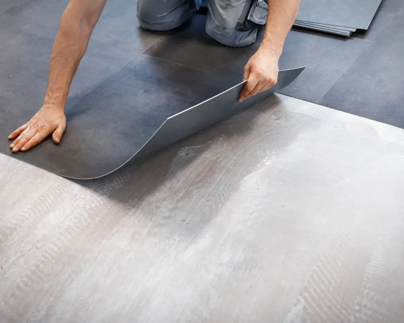 Person peeling back a gray floor covering during installation
