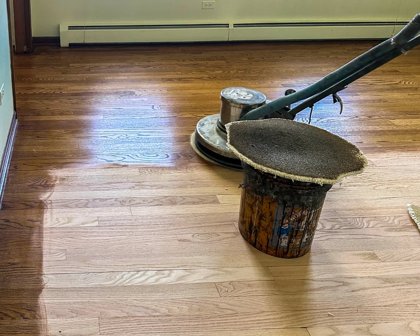 Floor buffer polishing a hardwood floor in a room