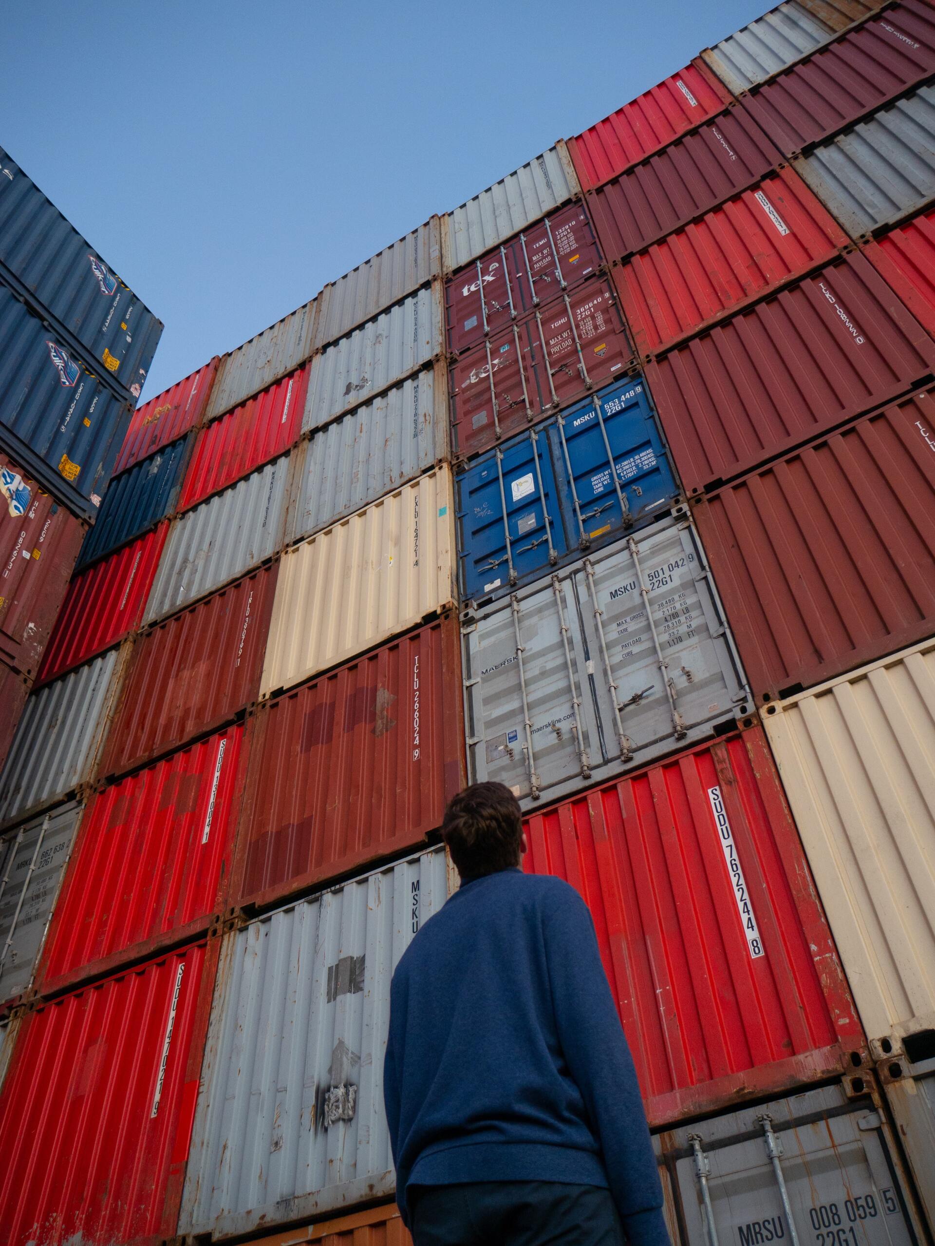 hombre parado frente a contenedores destinados para comercio exterior hombre parado frente a contenedores destinados para comercio exterior