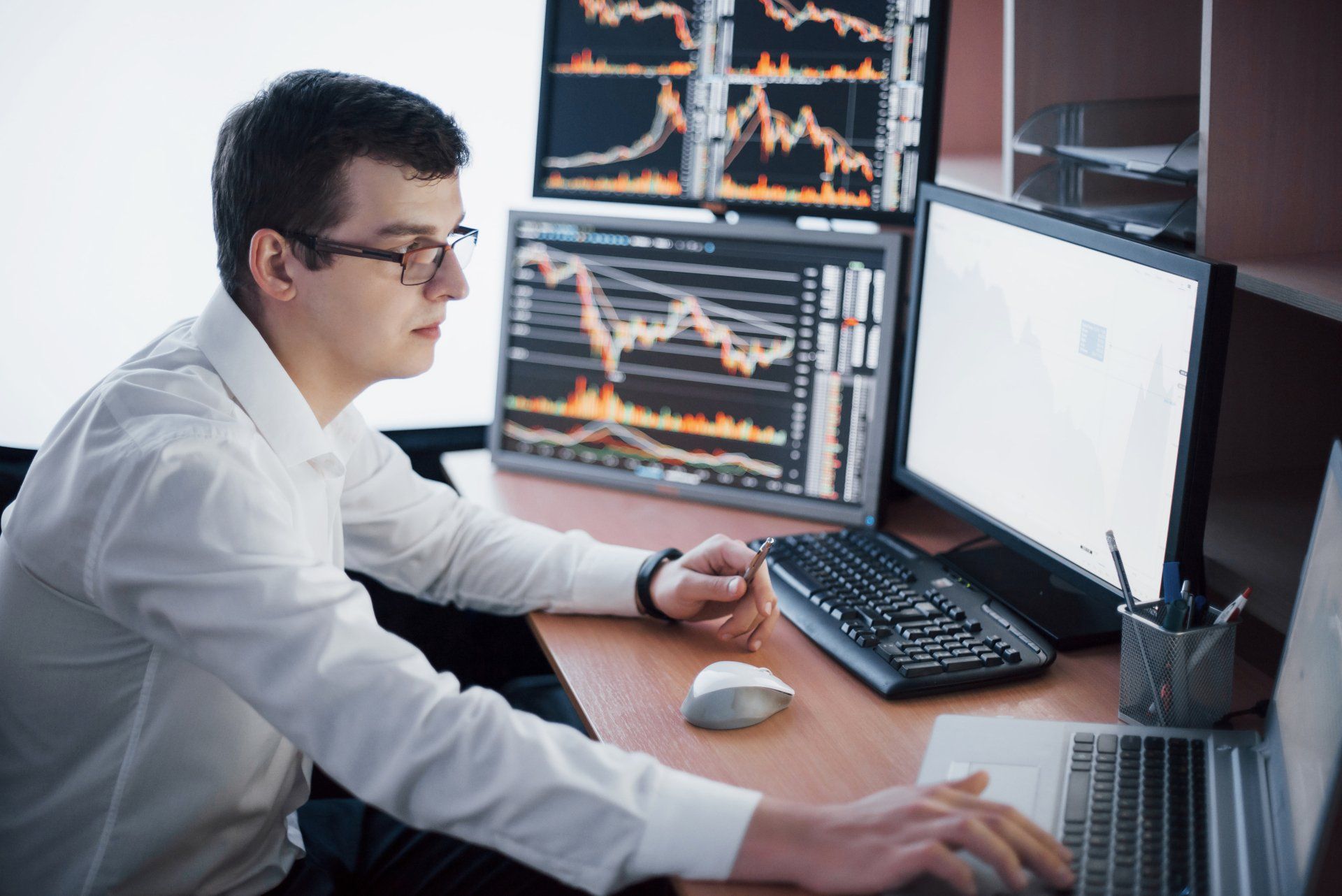 El corredor de bolsa en camisa está trabajando en una sala de monitoreo con pantallas. Concepto gráfico de la bolsa de comercio de forex finance. El corredor de bolsa en camisa está trabajando en una sala de monitoreo con pantallas. Concepto gráfico de la bolsa de comercio de forex finance.