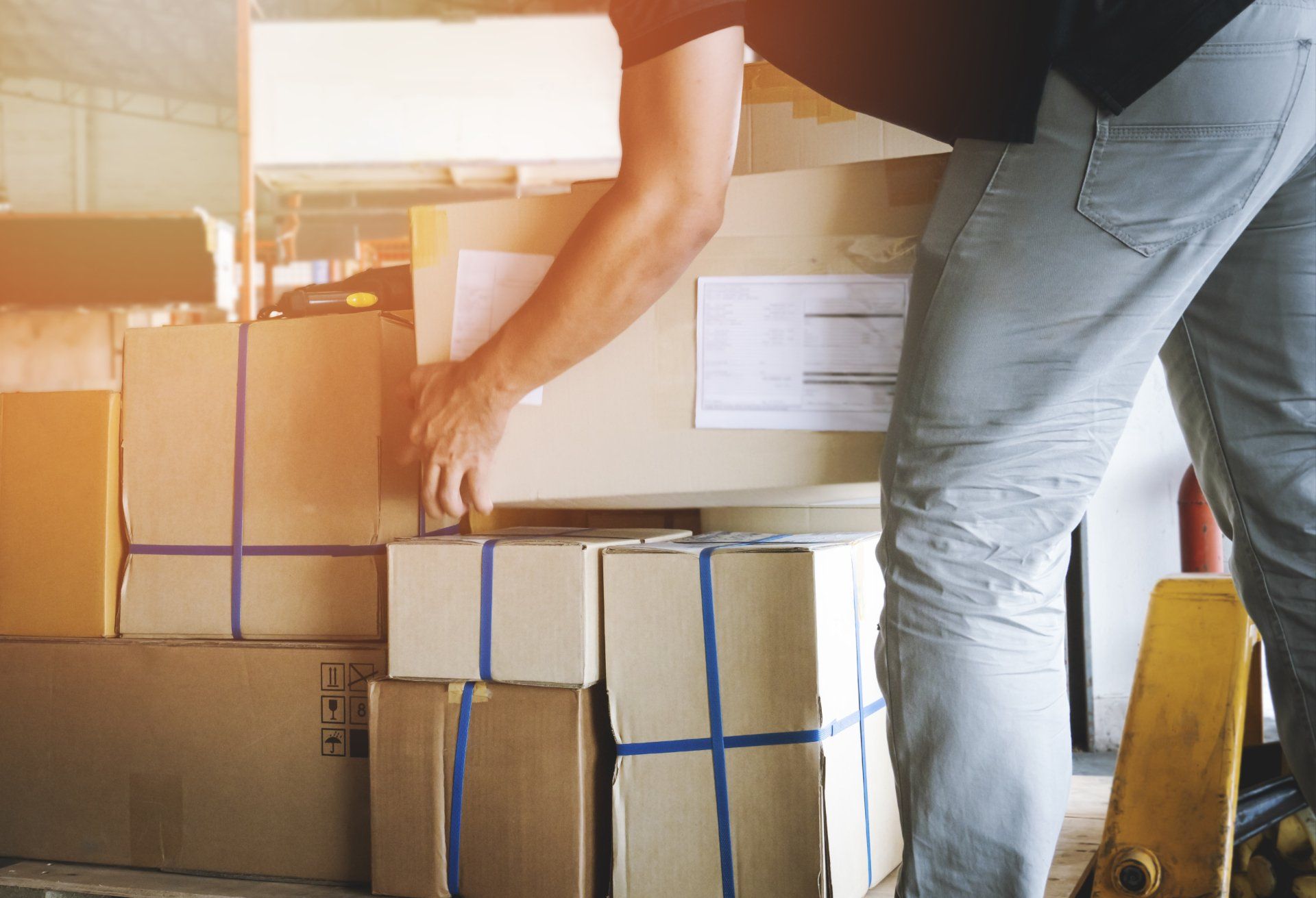 Trabajador courier levantando cajas de paquetes apilando en palé cajas de envío envío logística