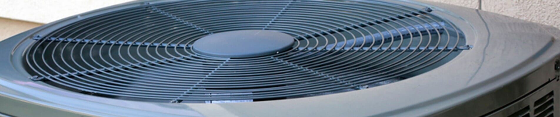 Close-up of a gray air conditioner unit with a circular fan grille on top