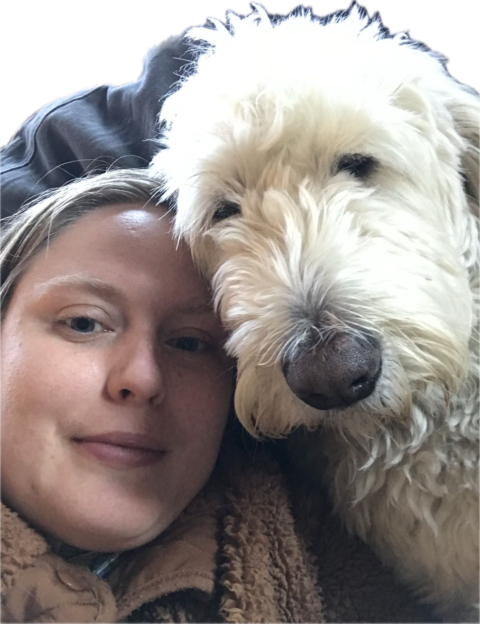 Woman cuddling a fluffy white dog, both close to the camera with calm expressions.