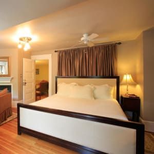 Bedroom with a large bed, brown curtains, and a bedside table with a lamp.