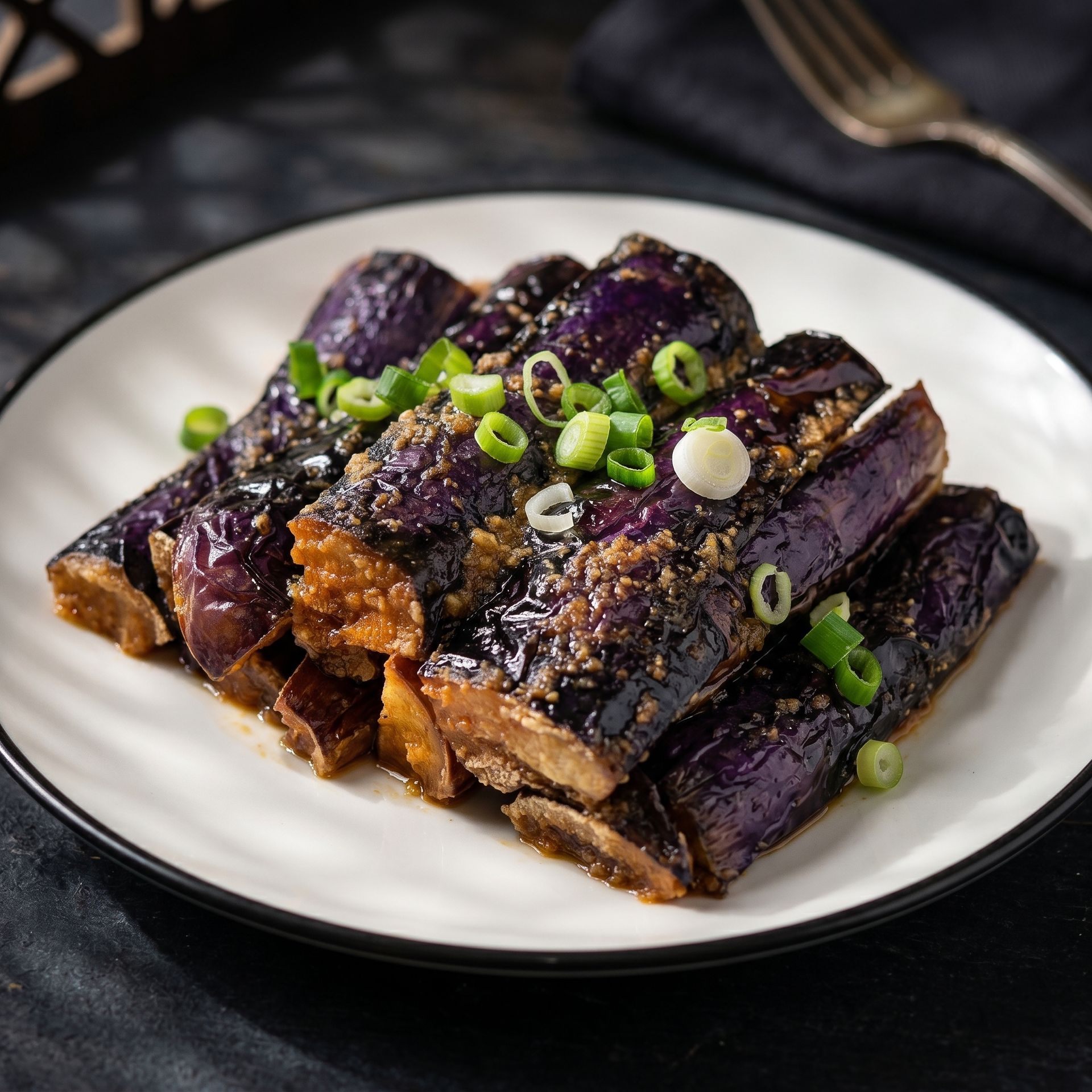 Glazed grilled eggplant slices topped with chopped green onions on a white plate