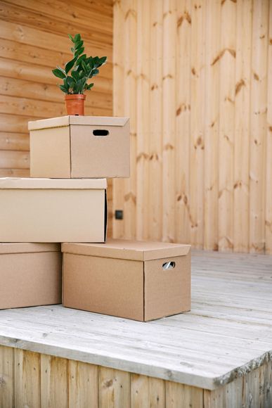 A stack of cardboard boxes sitting on top of each other on a wooden deck.