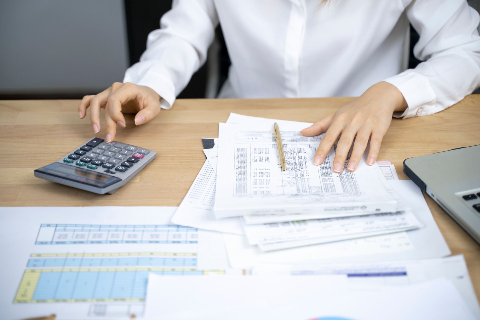 A woman is sitting at a desk using a calculator.