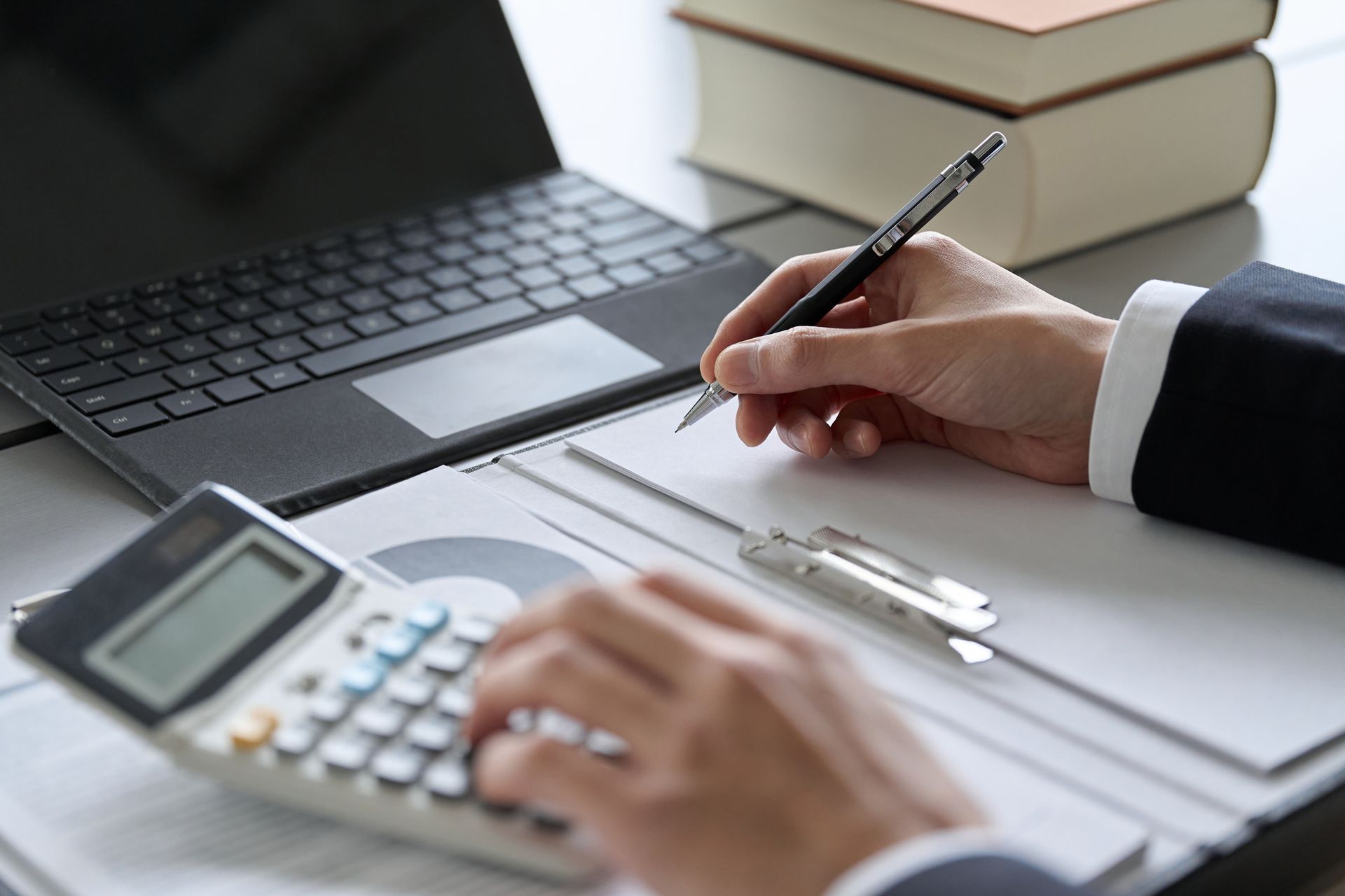 A person is using a calculator and writing on a piece of paper.