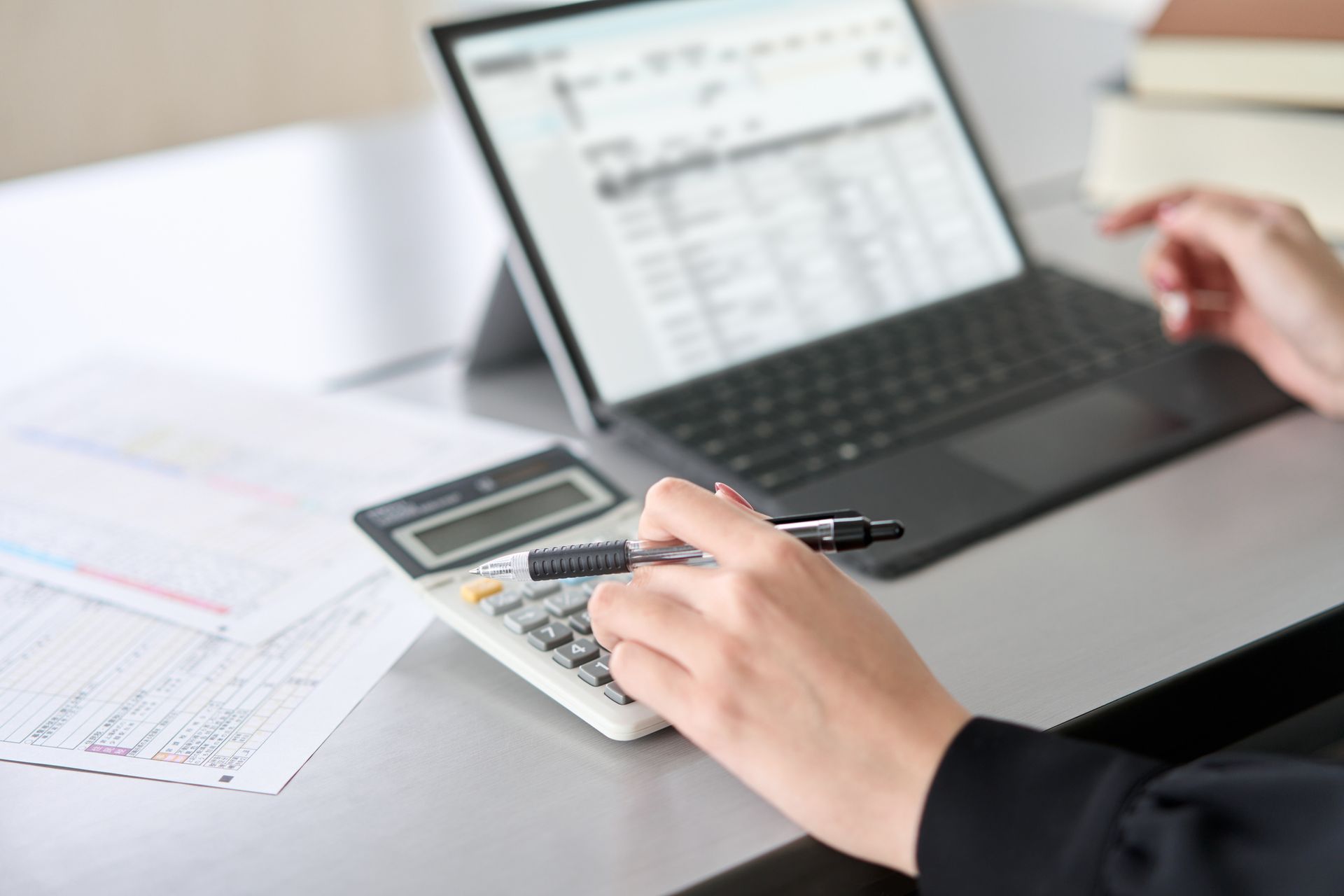 A person is using a laptop and a calculator at the same time.