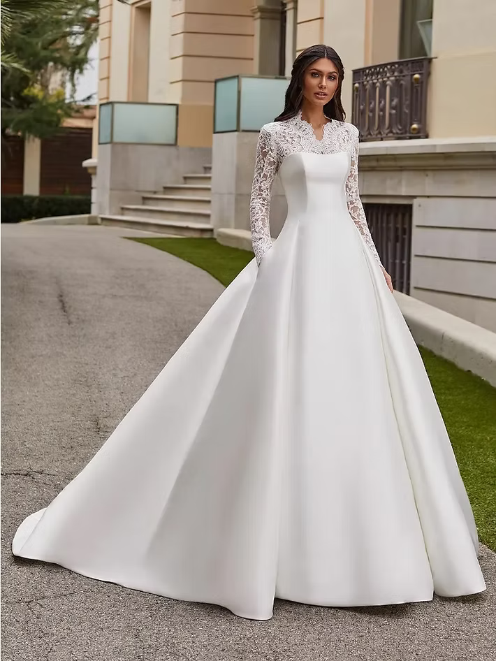 Woman in white wedding dress with lace sleeves and long train.