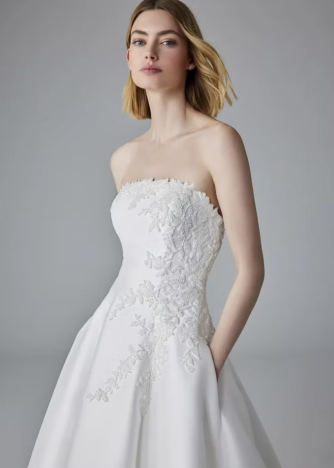 Woman in strapless white wedding gown with floral bodice detail.