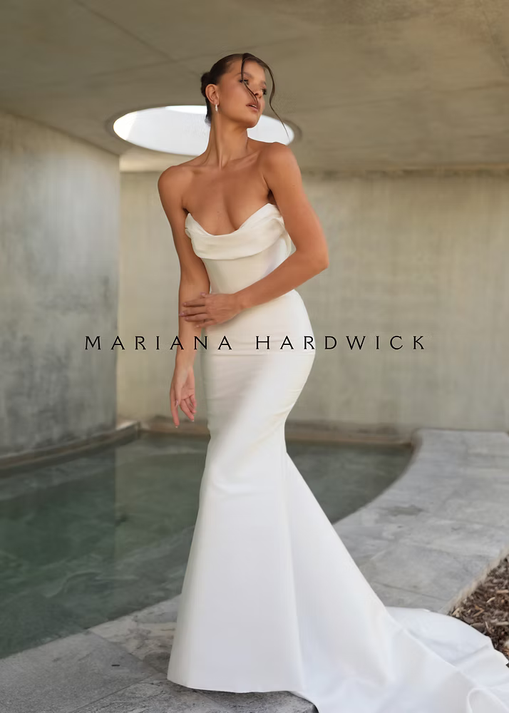 Woman in a strapless white wedding dress, standing near a pool.