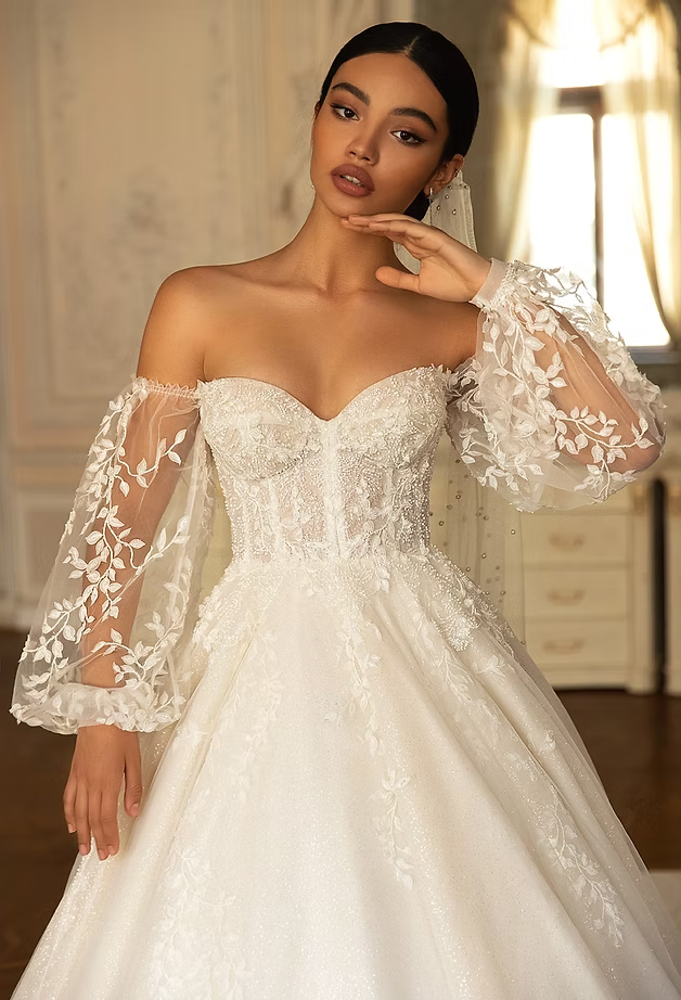 Woman in a white, off-the-shoulder wedding dress with puffy lace sleeves.