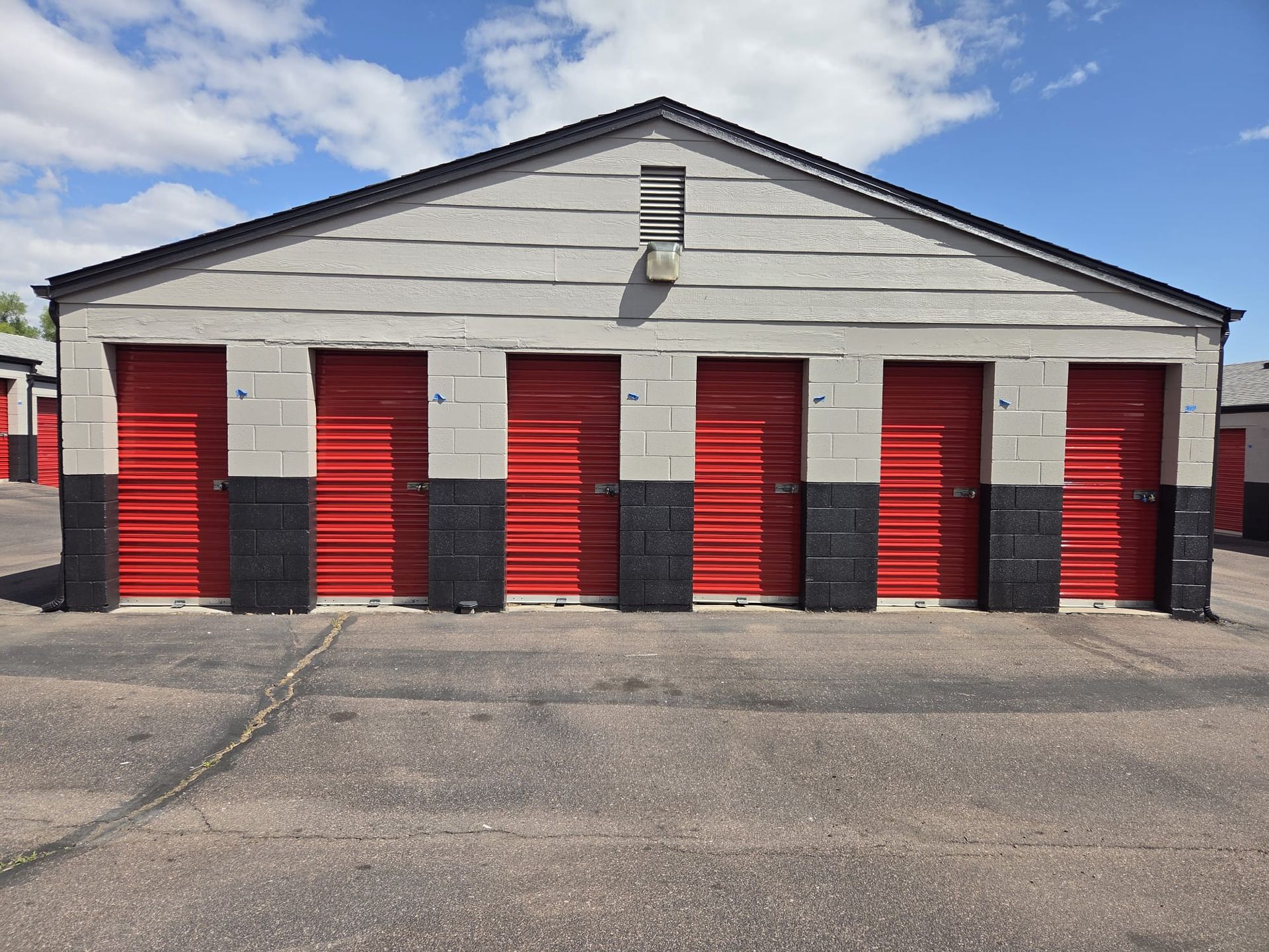 Row of red storage unit doors on a white building under a blue sky