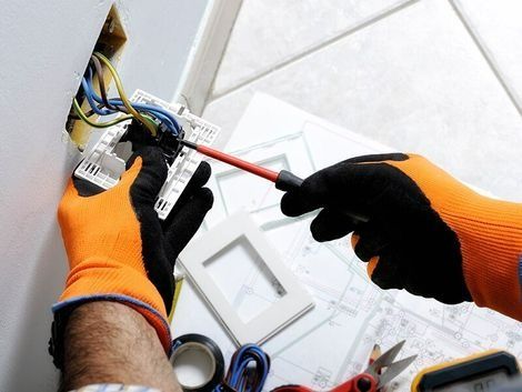 An Electrician is Working on a Light Switch With a Screwdriver — Himec Electrical In Withcott, QLD