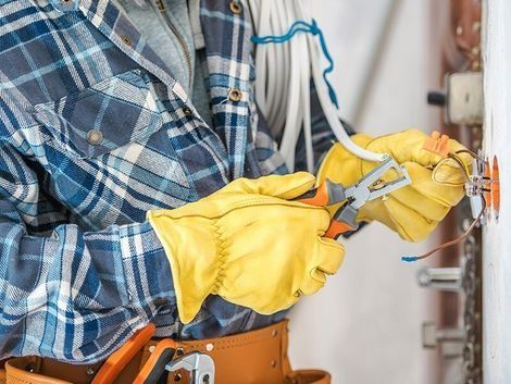 An Electrician is Working on an Electrical Outlet on a Wall — Himec Electrical In Withcott, QLD
